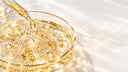 Capsula Petri con gel trasparente, scaglie d'oro 24K e bolle, pipetta di vetro che rilascia una goccia dorata, Chrissie Cosmetics