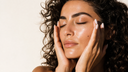 Primo piano di pelle idratata e rimpolpata con i palmi sulle guance, Chrissie Cosmetics